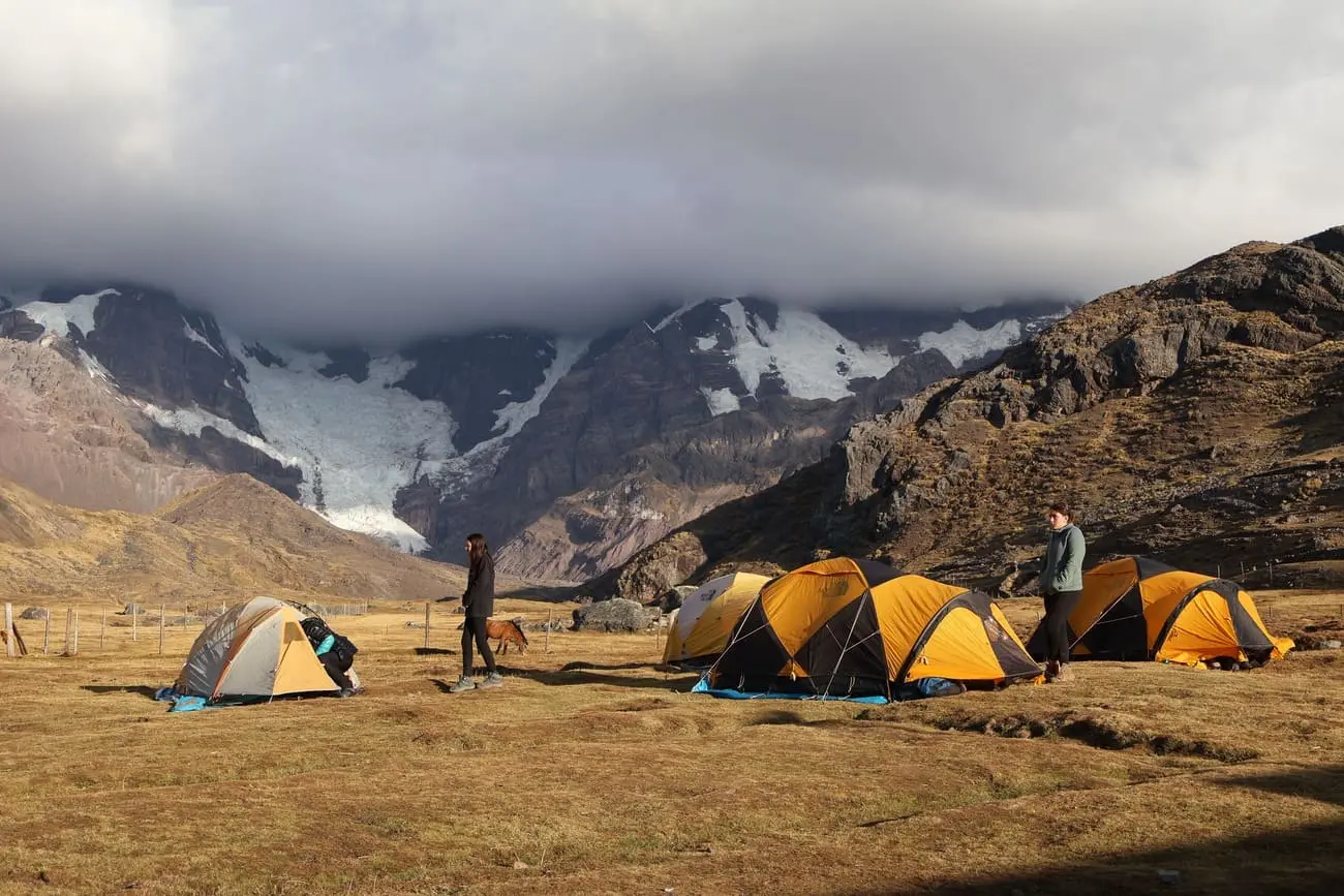 Campamento de alta montaña en el Trek de Ausangate en Perú, con tiendas instaladas bajo montañas andinas nevadas.