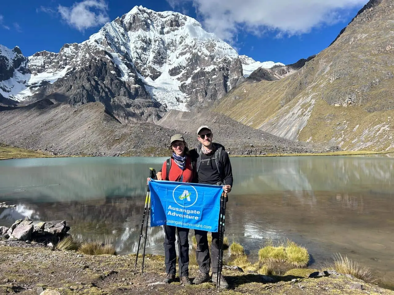 Couple hiking at Ausangate Lake with the snow-capped mountain in the background, Cusco, Peru.